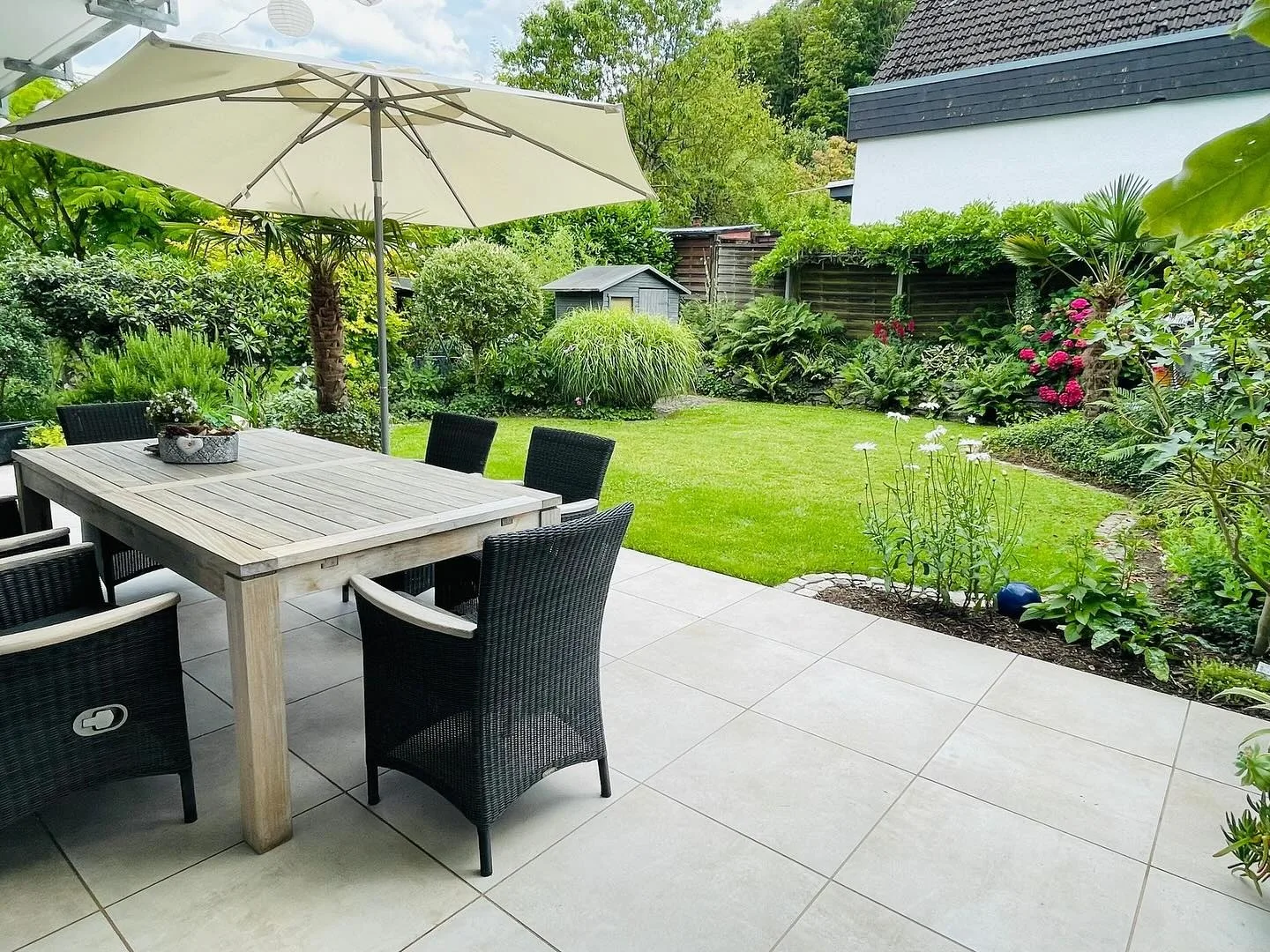 Fertiggestellte Terrasse mit Sonnenschirm und üppigem Beet – Projekt von Benitez Gartenbau in Bendorf-Sayn